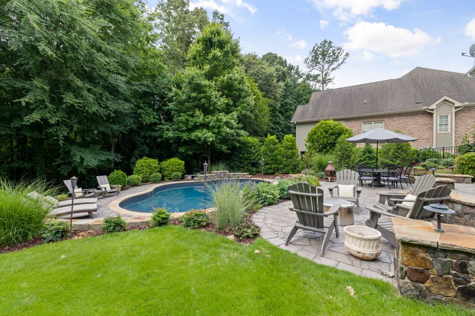A small backyard with tidy garden beds, a stone path, and a wooden bench with potted plants.