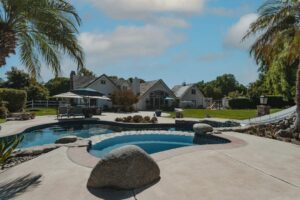 Natural swimming pool with planted filtration zone beside a traditional clear-water backyard pool
